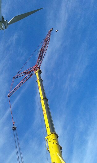 Hoher Mobilkran neben Windrad auf Baustelle