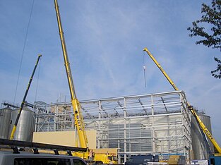 Hallenbau in Arbeit, unterstützt von drei großen Kränen
