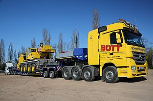 Schwerlasttransporter der einen mobilen Kran transportiert