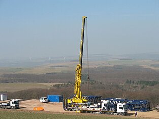 Mobilkran fährt seinen Auslegerarm im Windpark aus