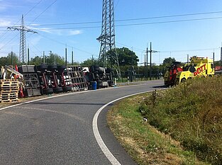 Weißer LKW liegt umgekippt in Kurve / am Straßenrand