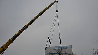 Schwerer Anhänger am Kranarm hängend in der Luft
