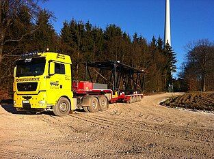 „Schwerlasttransporter bringt Windanlagenteil auf Straße am Waldrand
