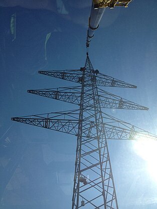Fotografie von unten unter dem Kranarm mit blauem Himmel im Hintergrund