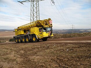 Gelber Mobilkran unterwegs auf Straße im Windpark